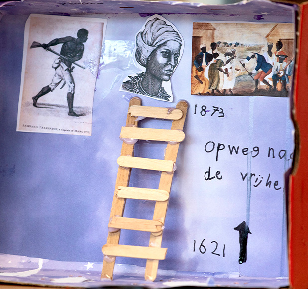 A student's handmade diorama from an educational workshop, depicting the struggle of enslaved people and the path to freedom with historical dates, showcasing art as a tool for learning about slavery history.
